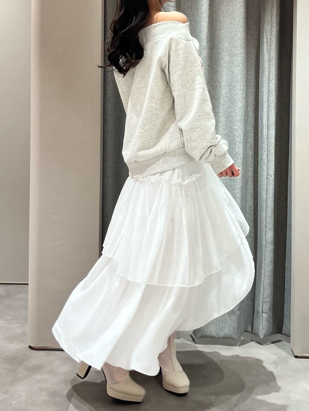 グレー系のスウェット、ホワイト系のスカート、ホワイト系のブーツを着用したレディースの春コーディネートの7枚目の写真