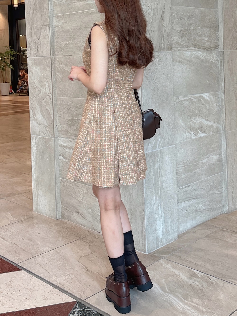 イエロー系のワンピース、ブラウン系のボストンバッグ、ブラウン系のローファーを着用したレディースの秋コーディネートの7枚目の写真