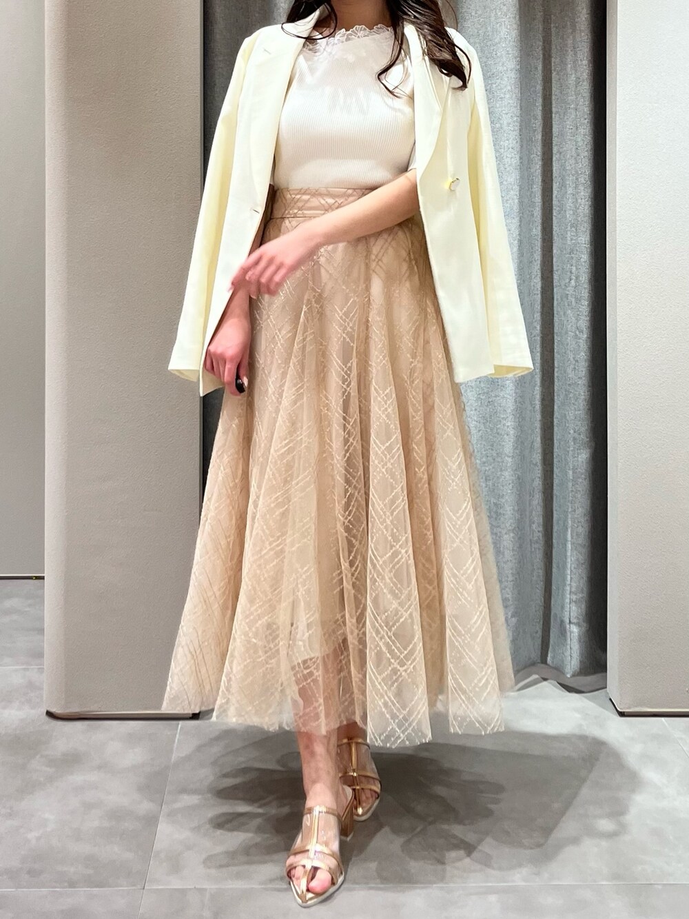 ホワイト系のニット/セーター、ホワイト系のテーラードジャケット、ベージュ系のスカートを着用したレディースの春コーディネートの4枚目の写真