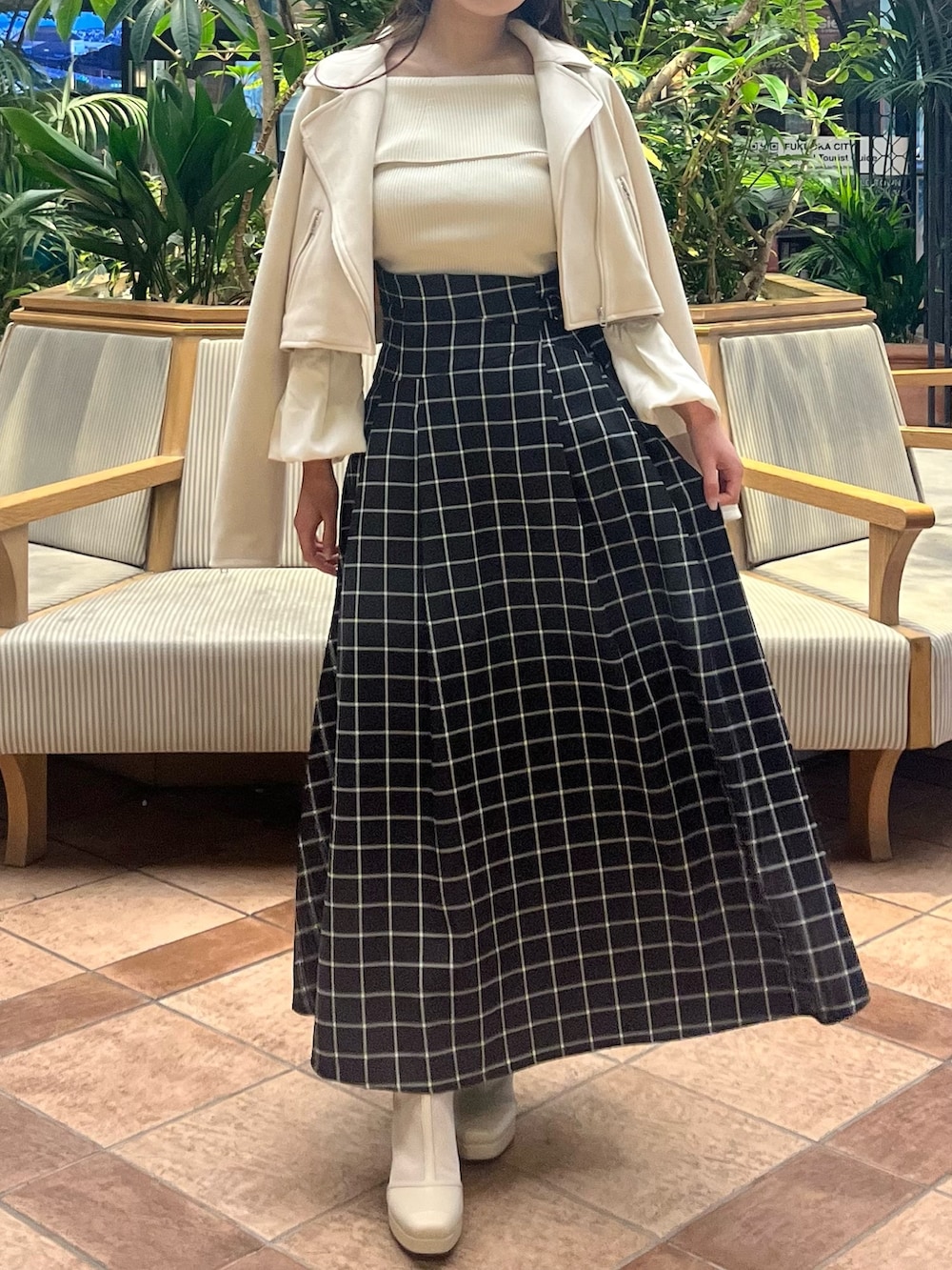 ホワイト系のライダースジャケット、ホワイト系のニット/セーター、ブラック系のスカートを着用したレディースの春コーディネートの2枚目の写真