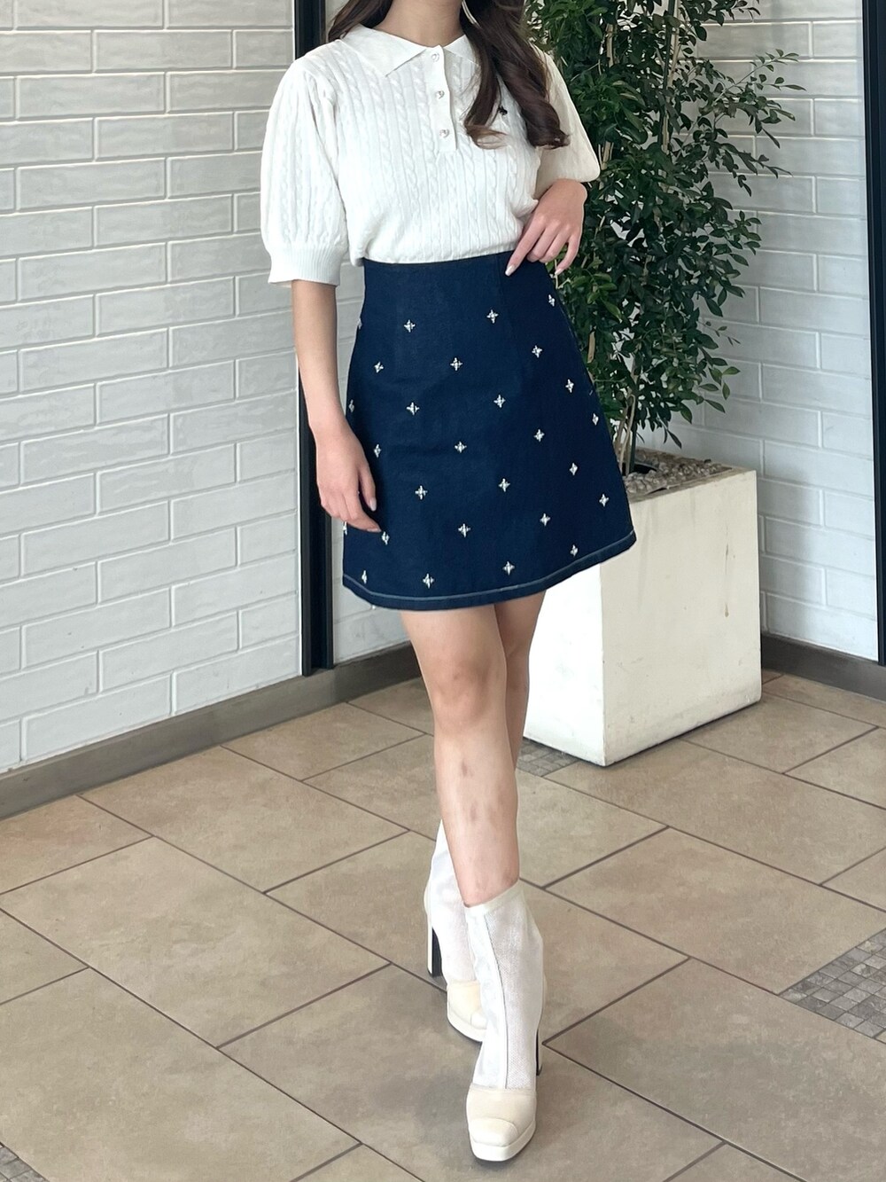 ホワイト系のニット/セーター、ブルー系のデニムスカート、ホワイト系のブーツを着用したレディースの春コーディネートの3枚目の写真