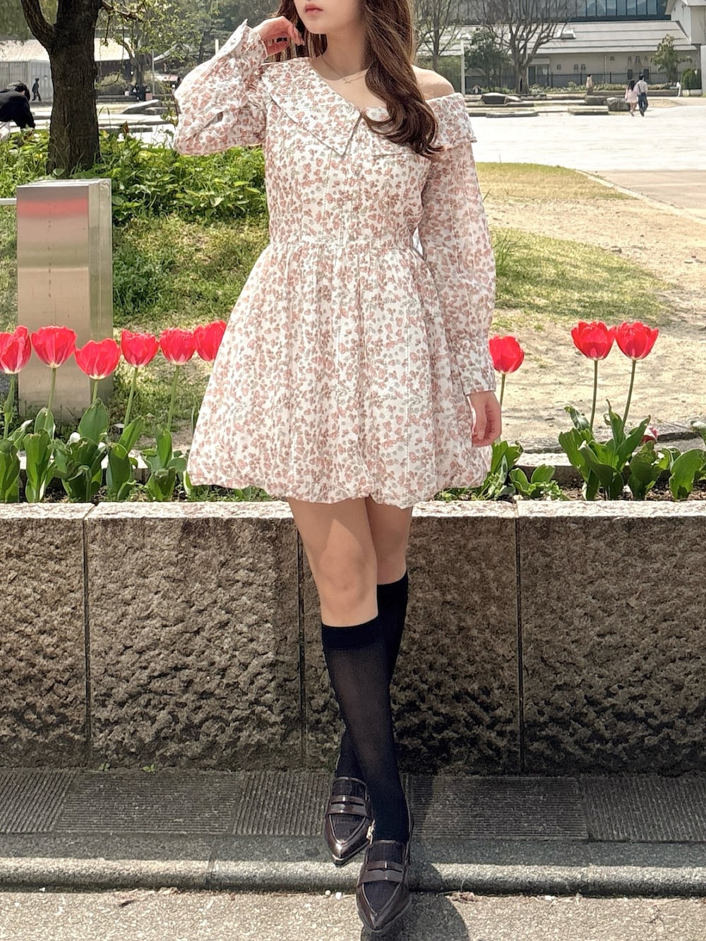 オレンジ系のワンピース、ブラウン系のローファーを着用したレディースの春コーディネートの2枚目の写真