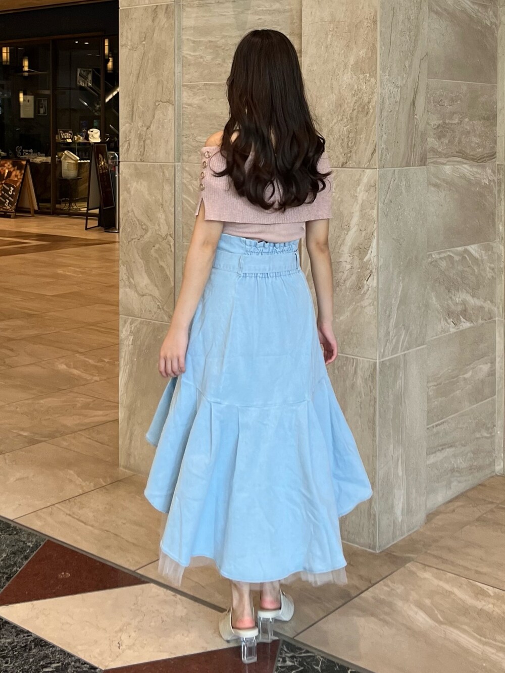 ピンク系のニット/セーター、ブルー系のスカート、ホワイト系のパンプスを着用したレディースの夏コーディネートの9枚目の写真