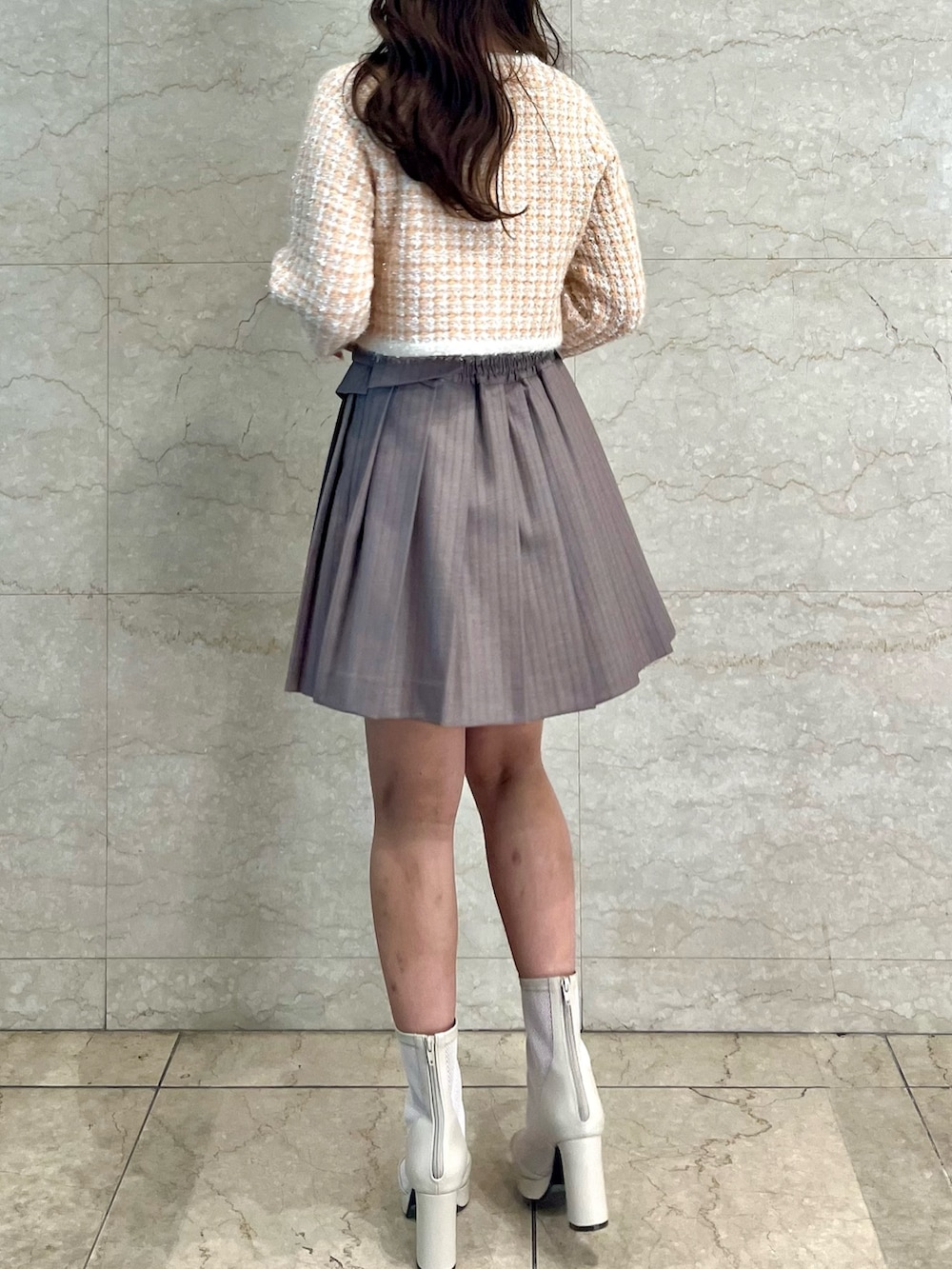 オレンジ系のノーカラージャケット、ベージュ系のスカート、ホワイト系のブーツを着用したレディースの冬コーディネートの4枚目の写真