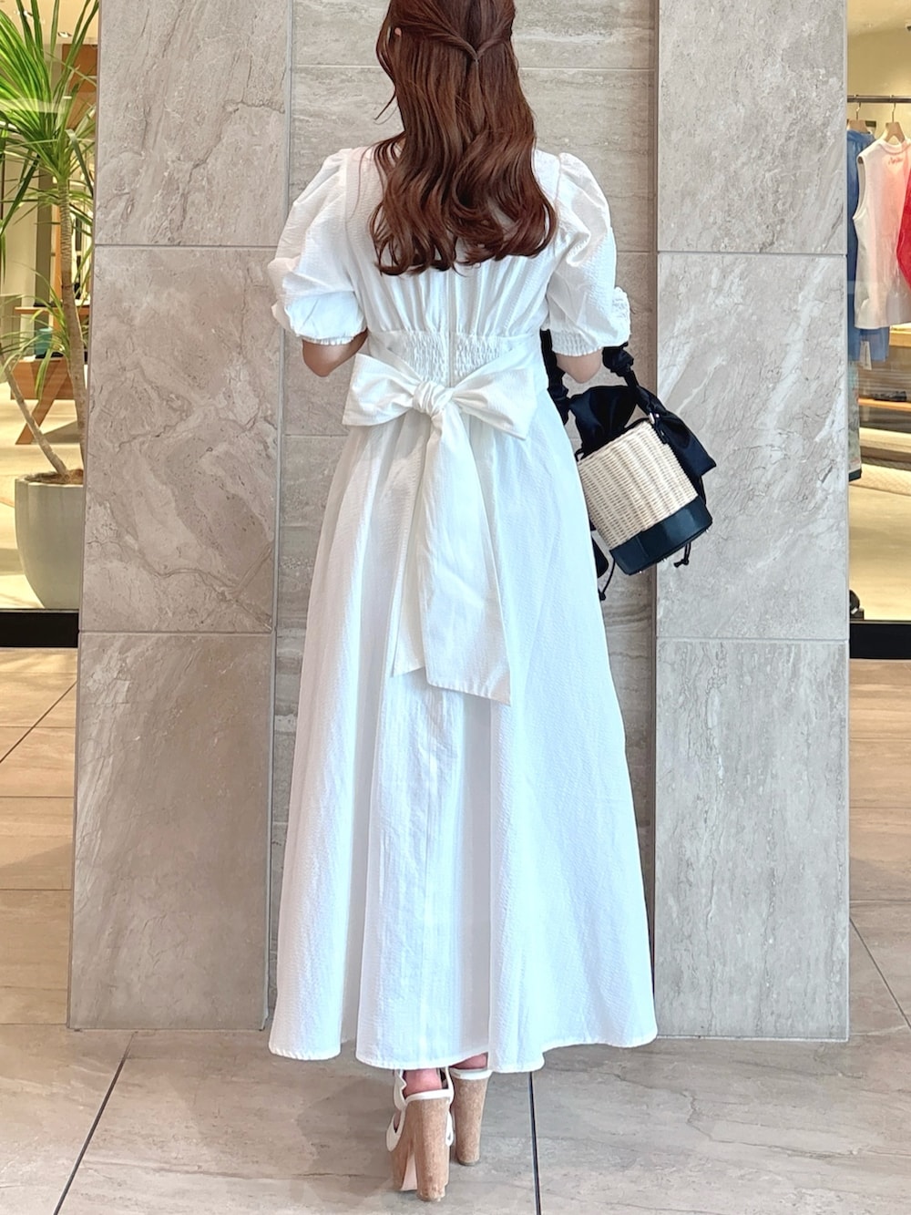 ホワイト系のワンピース、ブラック系のかごバッグ、ホワイト系のサンダルを着用したレディースの夏コーディネートの8枚目の写真