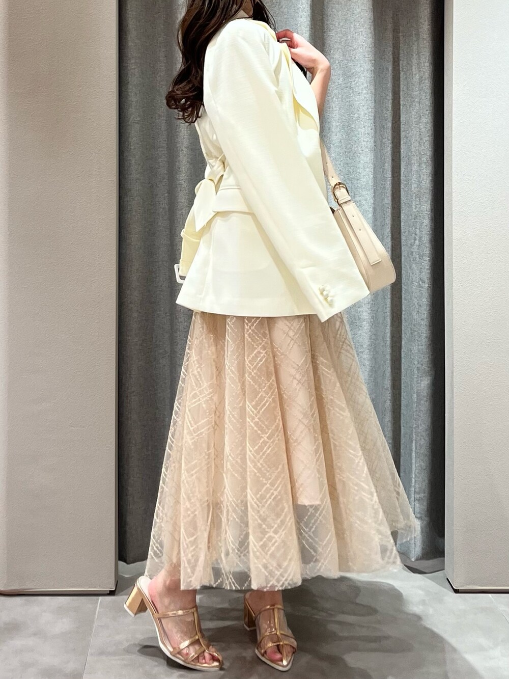 ホワイト系のニット/セーター、ホワイト系のテーラードジャケット、ベージュ系のスカートを着用したレディースの春コーディネートの7枚目の写真