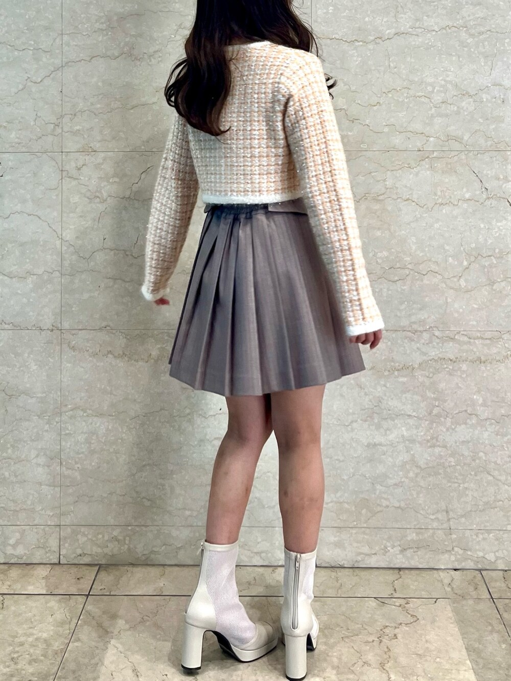 オレンジ系のノーカラージャケット、ベージュ系のスカート、ホワイト系のブーツを着用したレディースの冬コーディネートの6枚目の写真