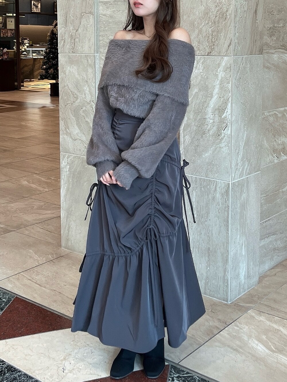 ブラウン系のニット/セーター、グレー系のスカート、その他のブーツを着用したレディースの冬コーディネートの4枚目の写真