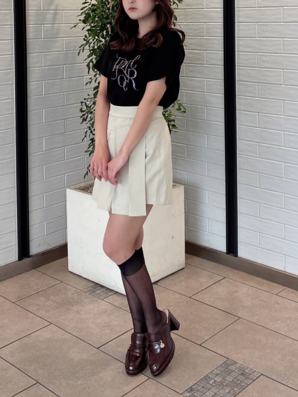 ブラウン系のパンプス、ブラック系のTシャツ/カットソー、ベージュ系のスカートを着用したレディースの夏コーディネートの2枚目の写真