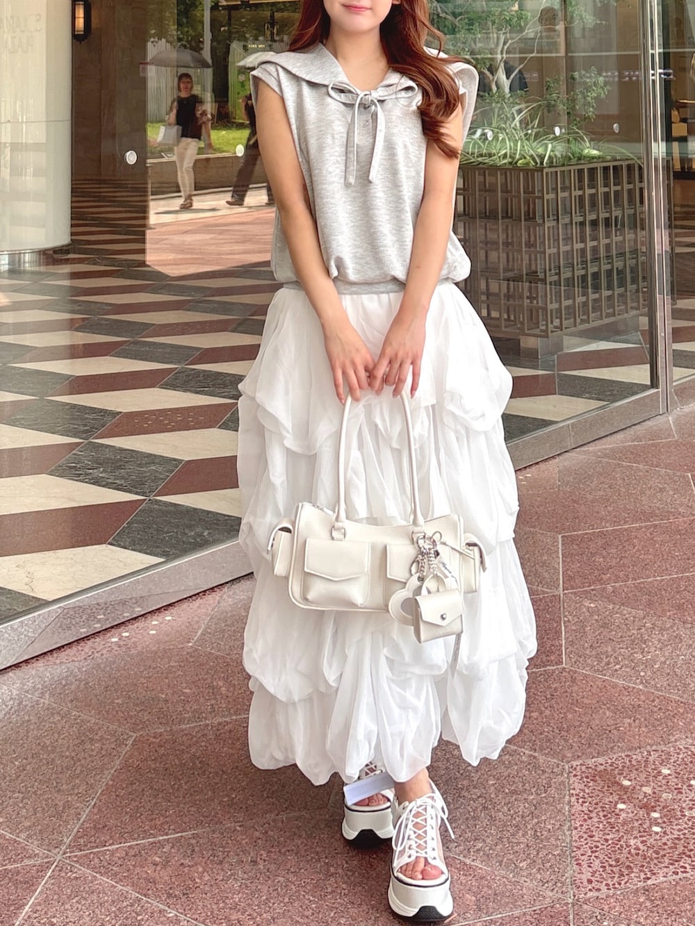 グレー系のTシャツ/カットソー、ホワイト系のスカート、ホワイト系のボストンバッグを着用したレディースの夏コーディネートの3枚目の写真