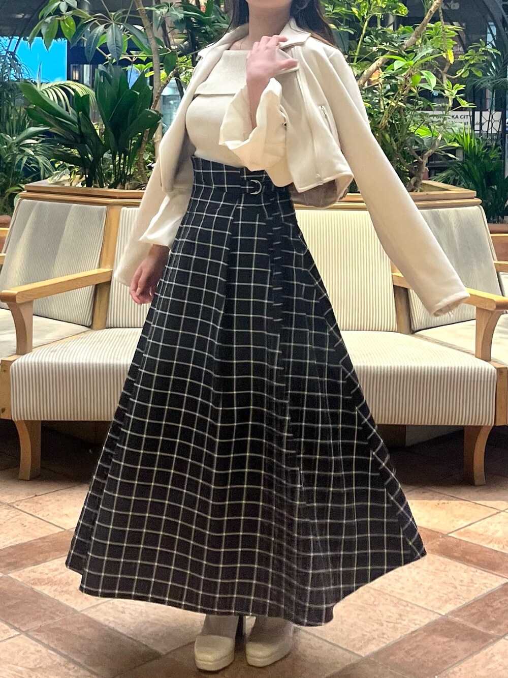 ホワイト系のライダースジャケット、ホワイト系のニット/セーター、ブラック系のスカートを着用したレディースの春コーディネートの4枚目の写真