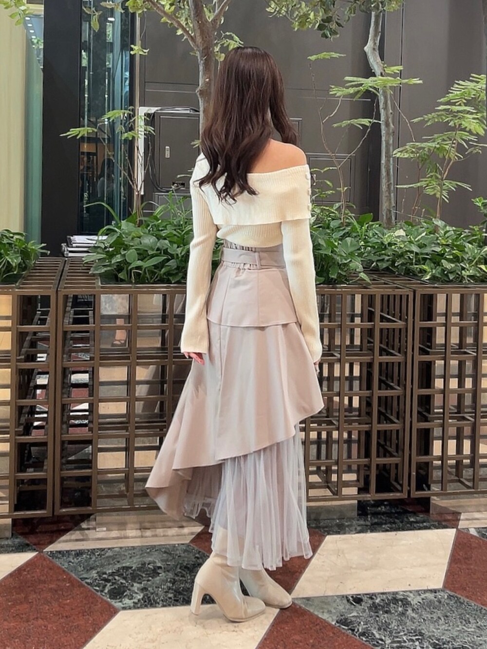 ホワイト系のニット/セーター、ベージュ系のスカート、ホワイト系のブーツを着用したレディースの冬コーディネートの3枚目の写真