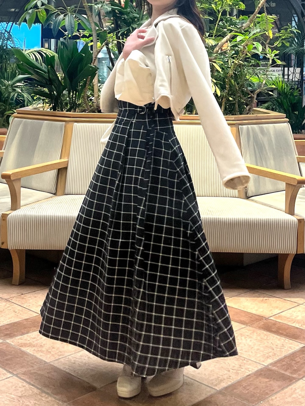 ホワイト系のライダースジャケット、ホワイト系のニット/セーター、ブラック系のスカートを着用したレディースの春コーディネートの5枚目の写真