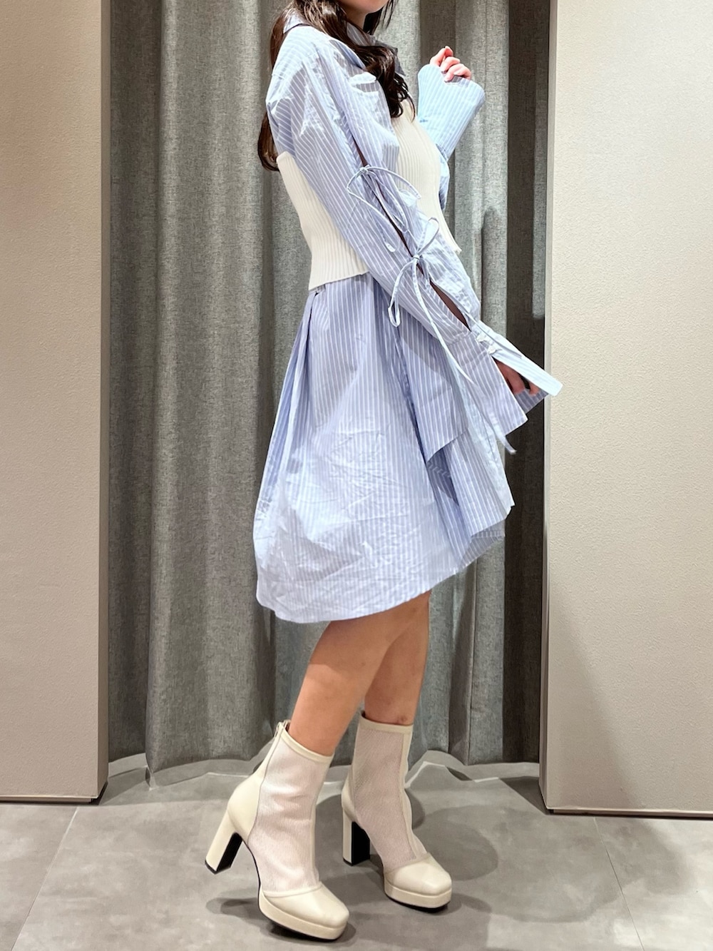 ホワイト系のキャミソール、ブルー系のシャツワンピース、ホワイト系のブーツを着用したレディースの冬コーディネートの7枚目の写真