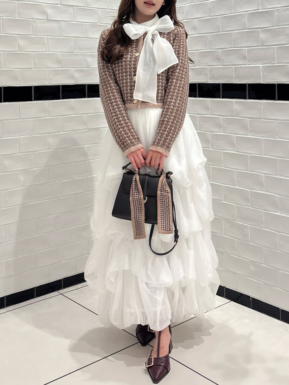ブラウン系のカーディガン/ボレロ、ホワイト系のシャツ/ブラウス、ブラウン系のショルダーバッグを着用したレディースの秋コーディネートの4枚目の写真