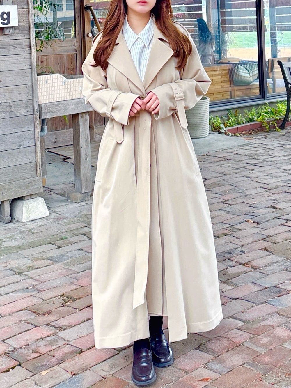 ベージュ系のトレンチコートを着用したレディースの春コーディネートの3枚目の写真