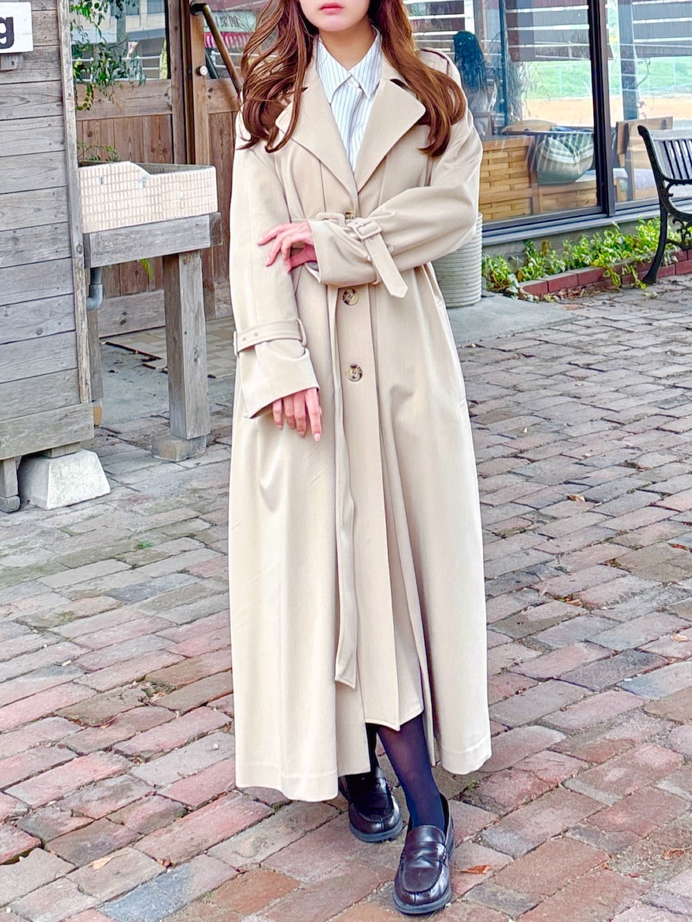 ベージュ系のトレンチコートを着用したレディースの春コーディネートの2枚目の写真