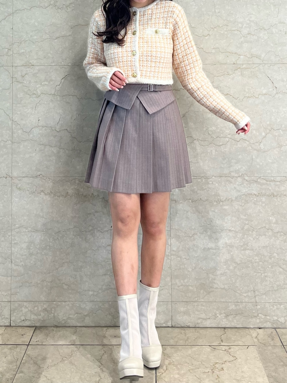 オレンジ系のノーカラージャケット、ベージュ系のスカート、ホワイト系のブーツを着用したレディースの冬コーディネートの2枚目の写真