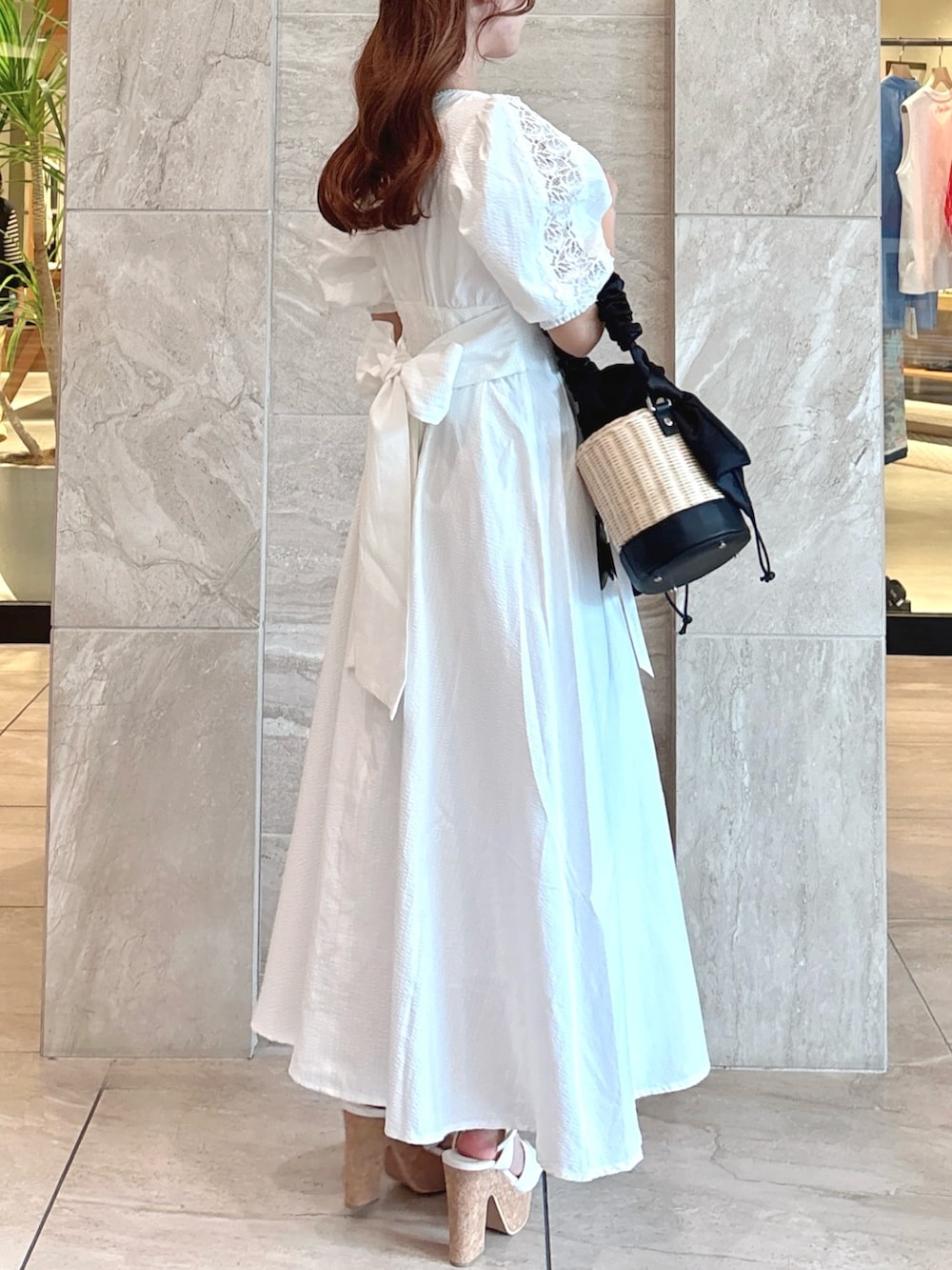 ホワイト系のワンピース、ブラック系のかごバッグ、ホワイト系のサンダルを着用したレディースの夏コーディネートの7枚目の写真