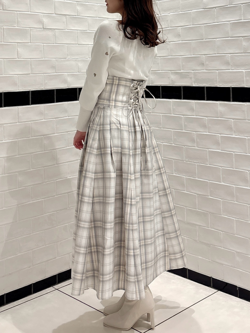 ホワイト系のニット/セーター、ホワイト系のスカート、ホワイト系のブーツを着用したレディースの冬コーディネートの3枚目の写真