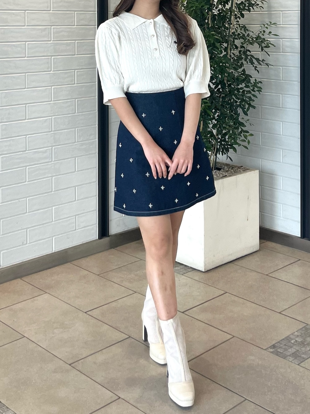 ホワイト系のニット/セーター、ブルー系のデニムスカート、ホワイト系のブーツを着用したレディースの春コーディネートの2枚目の写真