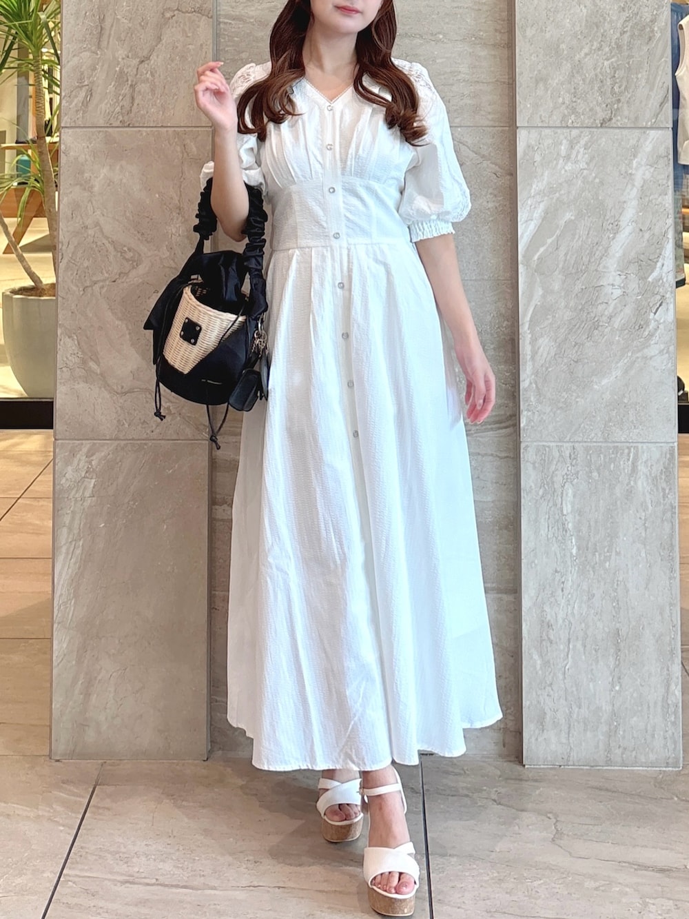 ホワイト系のワンピース、ブラック系のかごバッグ、ホワイト系のサンダルを着用したレディースの夏コーディネートの3枚目の写真