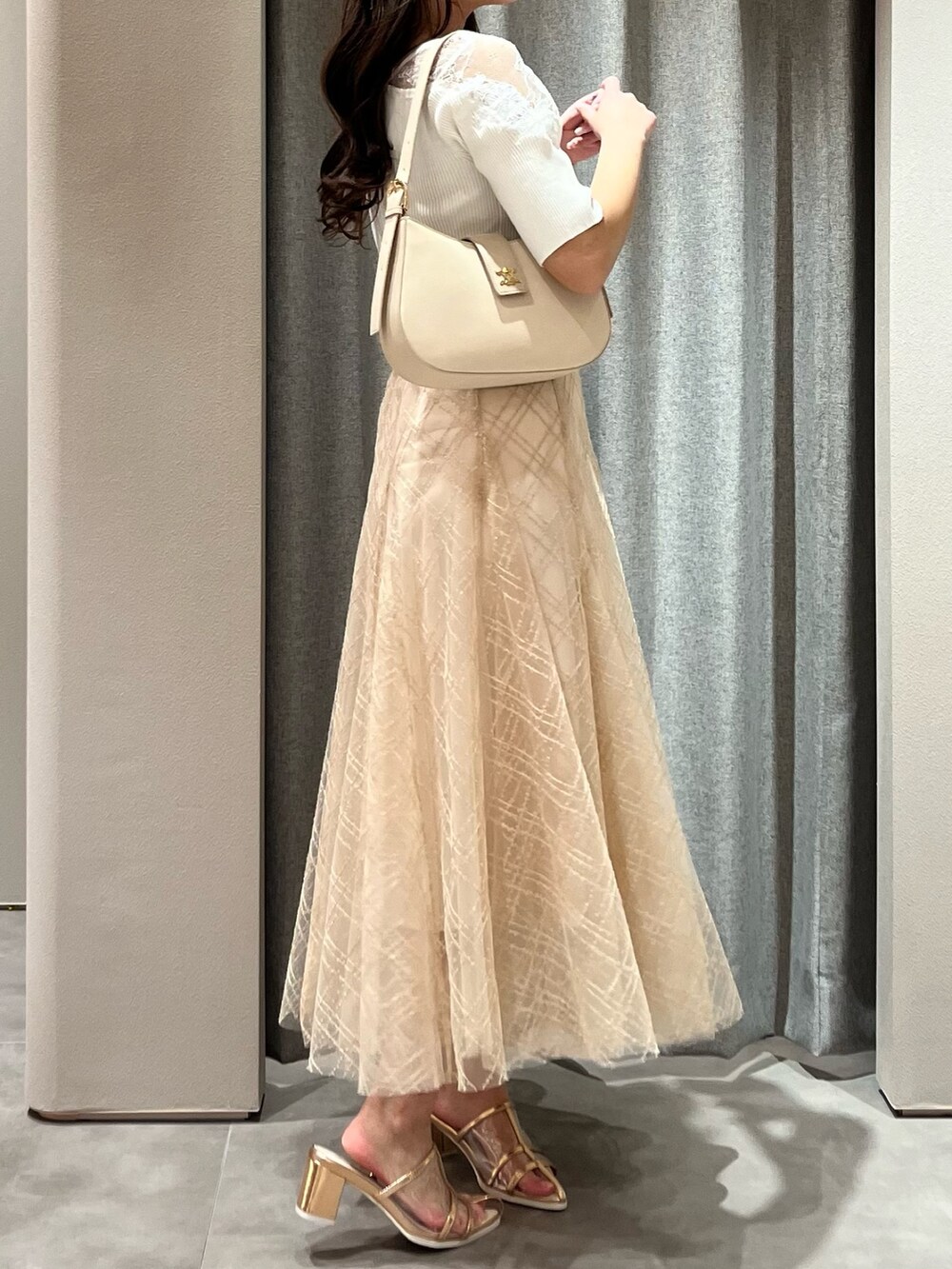 ホワイト系のニット/セーター、ベージュ系のスカート、ゴールド系のパンプスを着用したレディースの春コーディネートの7枚目の写真