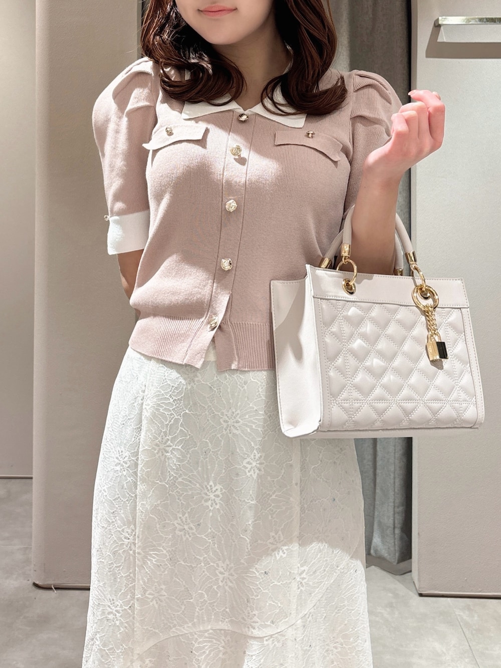 ピンク系のニット/セーター、ピンク系のハンドバッグ、ホワイト系のスカートを着用したレディースの春コーディネートの9枚目の写真