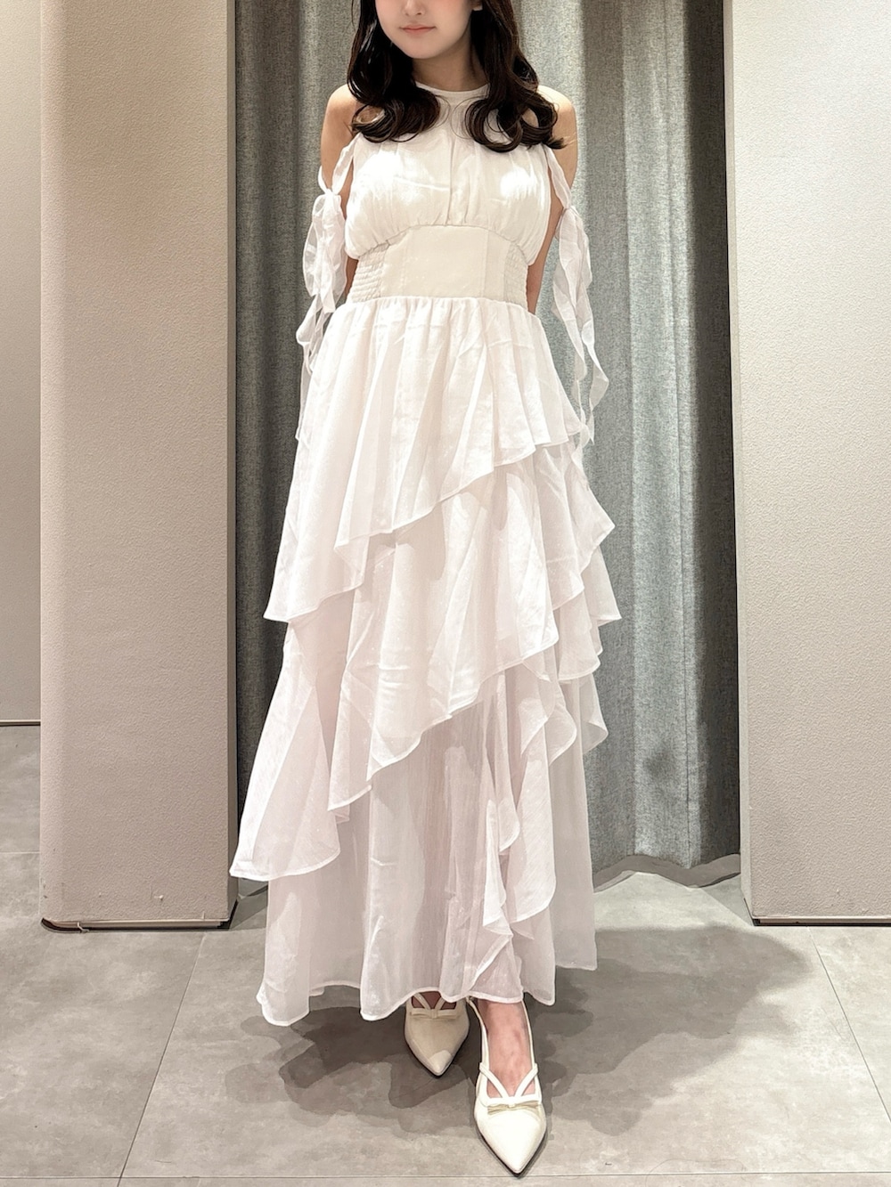 ピンク系のワンピース、シルバー系のショルダーバッグ、ホワイト系のパンプスを着用したレディースの夏コーディネートの5枚目の写真