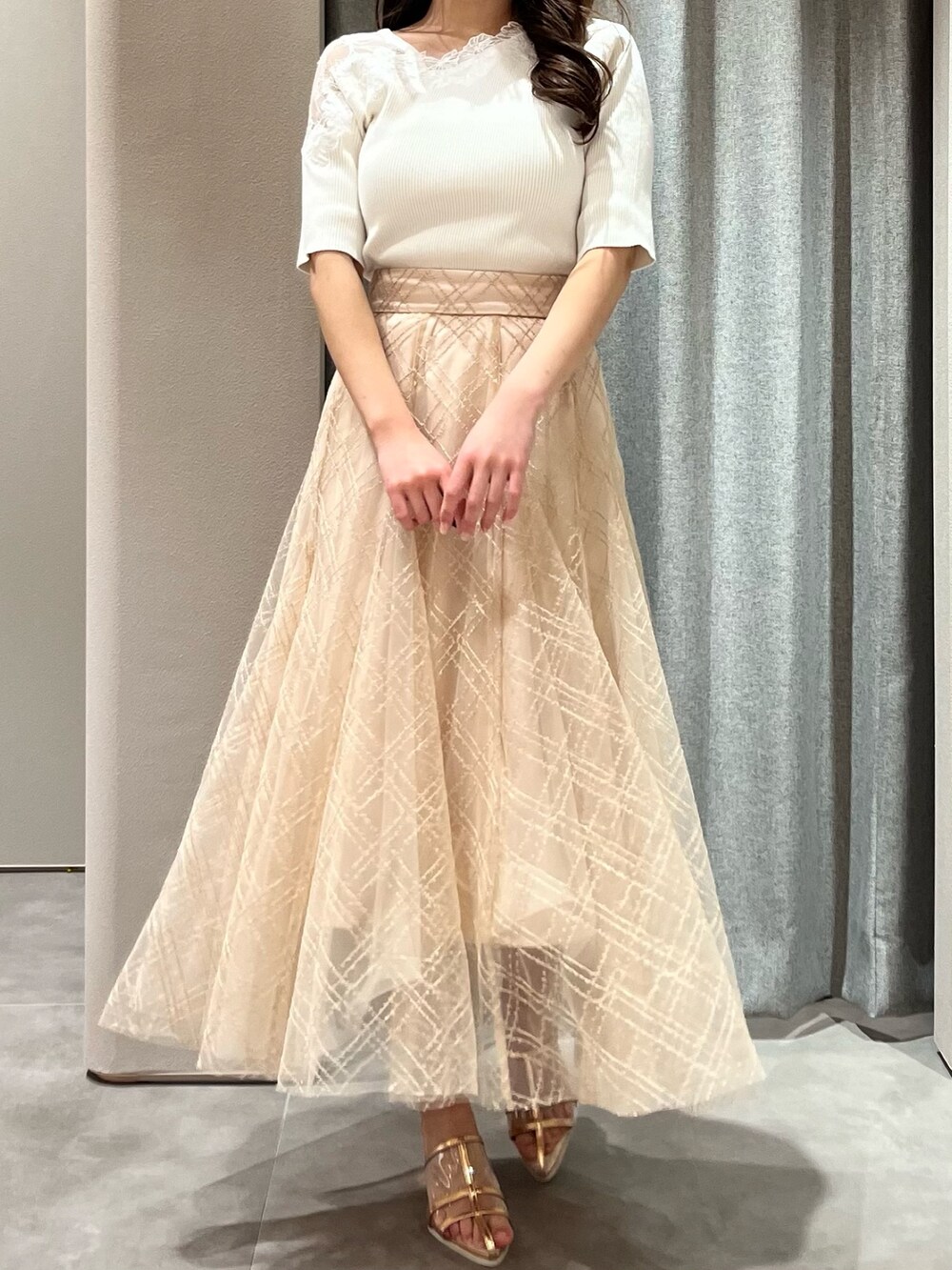 ホワイト系のニット/セーター、ベージュ系のスカート、ゴールド系のパンプスを着用したレディースの春コーディネートの3枚目の写真