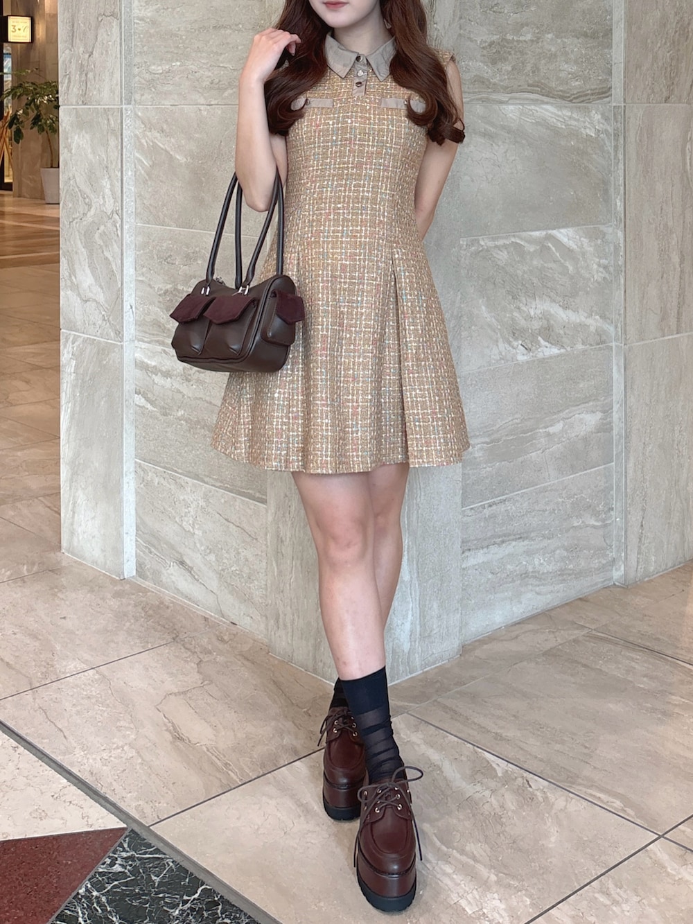 イエロー系のワンピース、ブラウン系のボストンバッグ、ブラウン系のローファーを着用したレディースの秋コーディネートの2枚目の写真