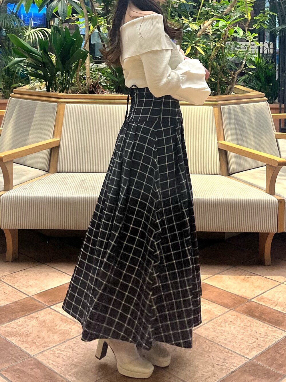 ホワイト系のニット/セーター、ブラック系のスカート、ホワイト系のブーツを着用したレディースの春コーディネートの6枚目の写真