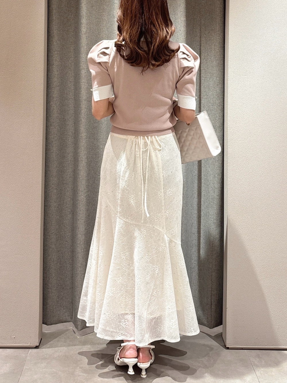 ピンク系のニット/セーター、ピンク系のハンドバッグ、ホワイト系のスカートを着用したレディースの春コーディネートの8枚目の写真