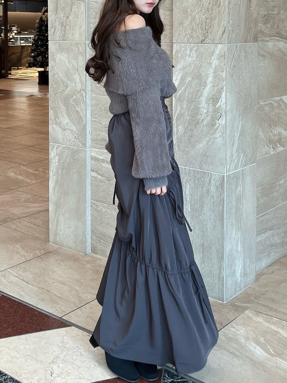 ブラウン系のニット/セーター、グレー系のスカート、その他のブーツを着用したレディースの冬コーディネートの7枚目の写真