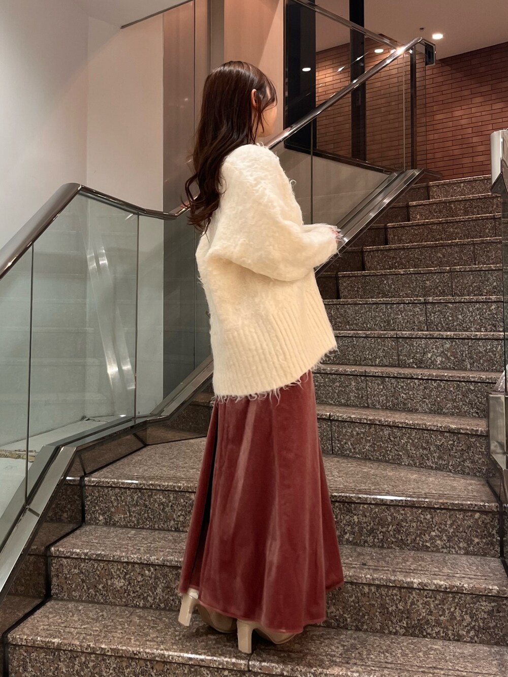 ホワイト系のカーディガン/ボレロ、グレー系のニット/セーター、ピンク系のワンピースを着用したレディースの冬コーディネートの2枚目の写真