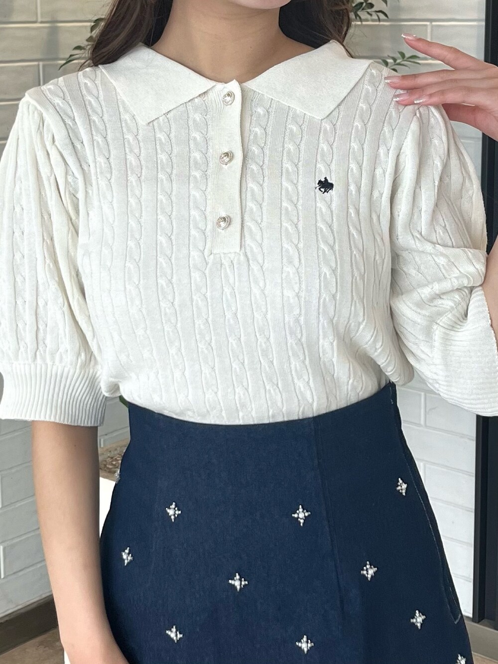 ホワイト系のニット/セーター、ブルー系のデニムスカート、ホワイト系のブーツを着用したレディースの春コーディネートの7枚目の写真