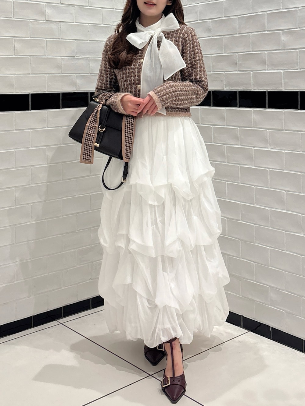 ブラウン系のカーディガン/ボレロ、ホワイト系のシャツ/ブラウス、ブラウン系のショルダーバッグを着用したレディースの秋コーディネートの2枚目の写真