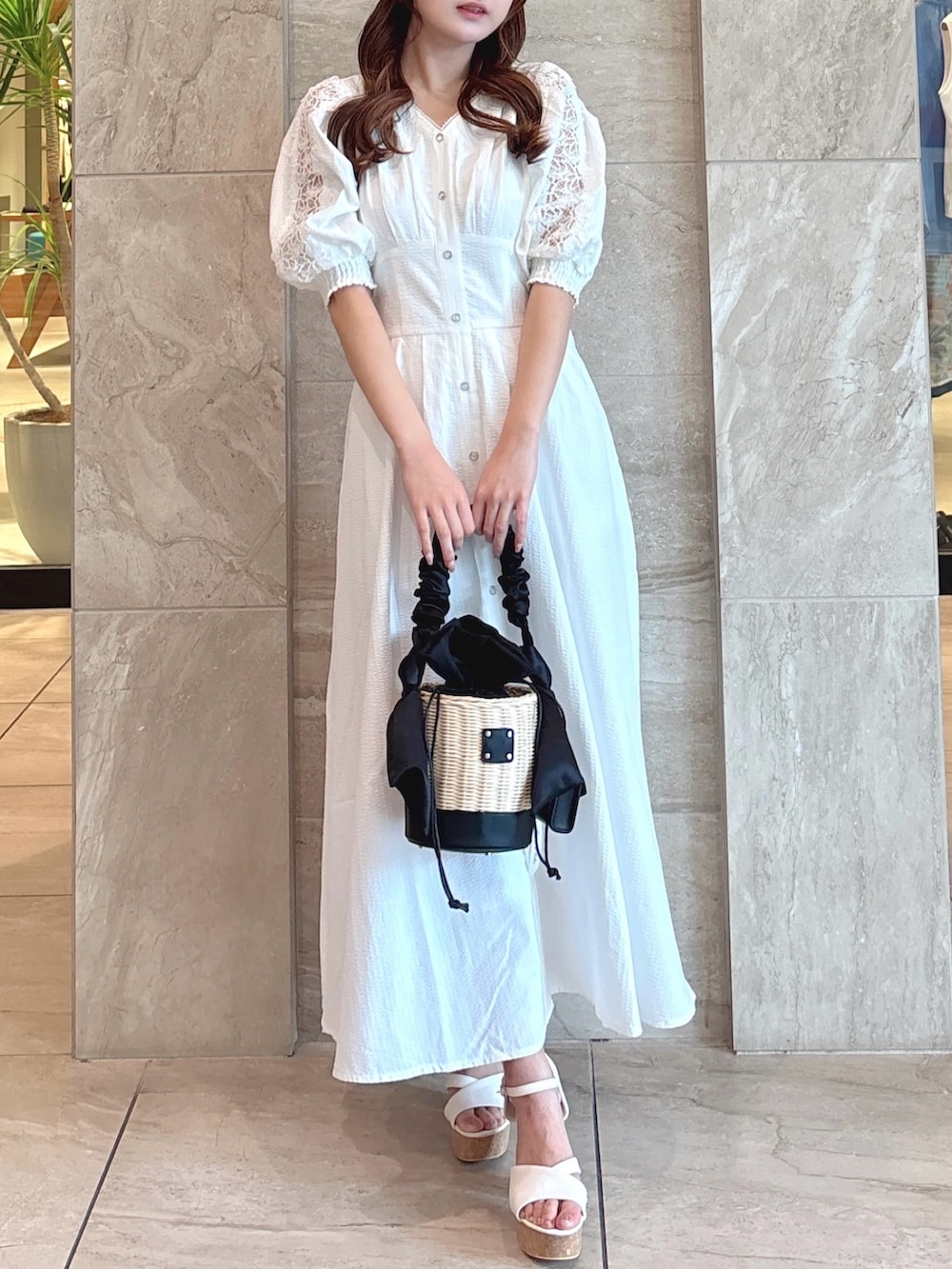 ホワイト系のワンピース、ブラック系のかごバッグ、ホワイト系のサンダルを着用したレディースの夏コーディネートの2枚目の写真