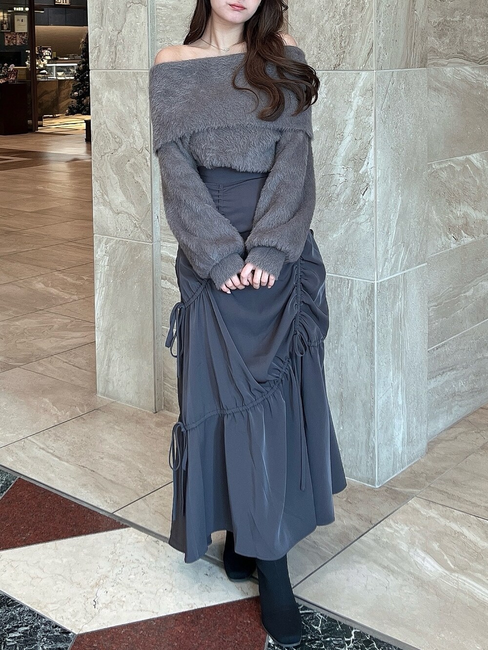 ブラウン系のニット/セーター、グレー系のスカート、その他のブーツを着用したレディースの冬コーディネートの2枚目の写真