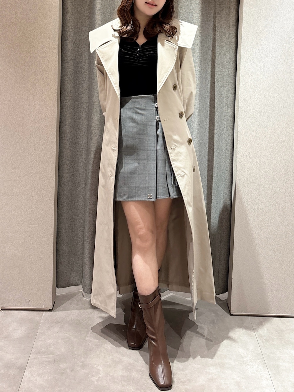 ブラック系のTシャツ/カットソー、ベージュ系のトレンチコート、グレー系のスカートを着用したレディースの春コーディネートの2枚目の写真