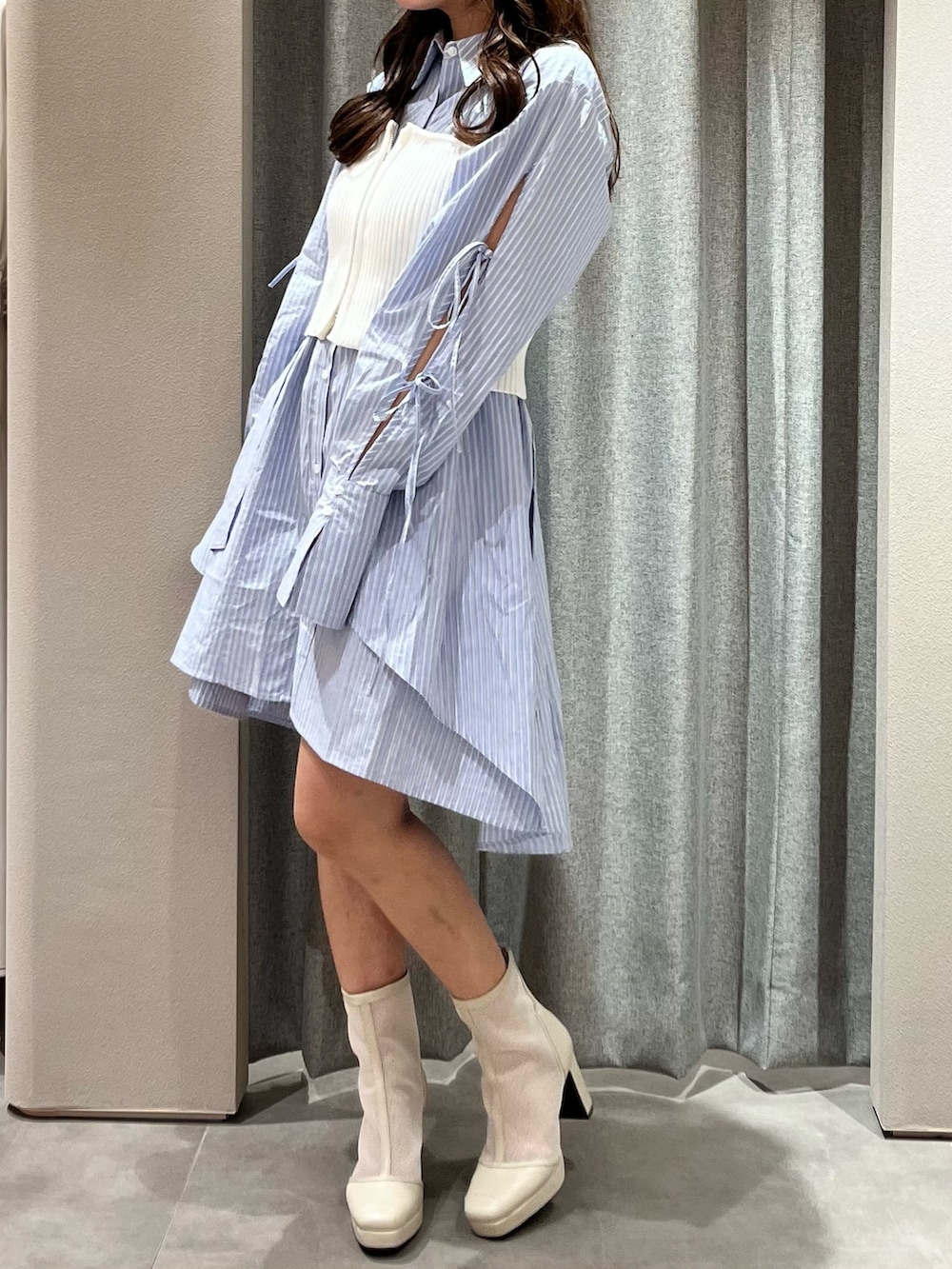 ホワイト系のキャミソール、ブルー系のシャツワンピース、ホワイト系のブーツを着用したレディースの冬コーディネートの6枚目の写真