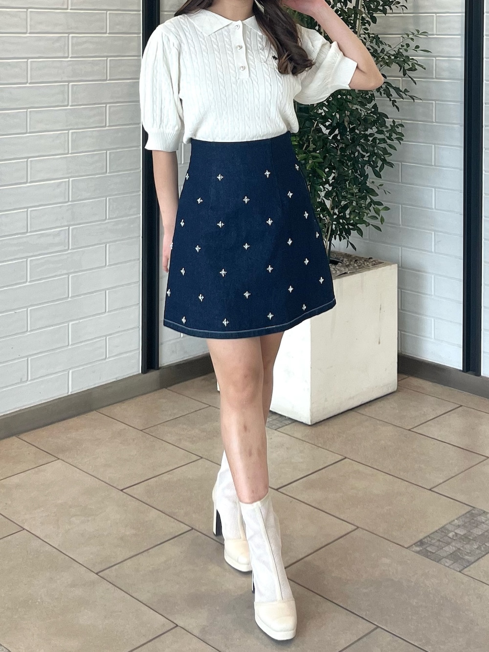 ホワイト系のニット/セーター、ブルー系のデニムスカート、ホワイト系のブーツを着用したレディースの春コーディネートの4枚目の写真