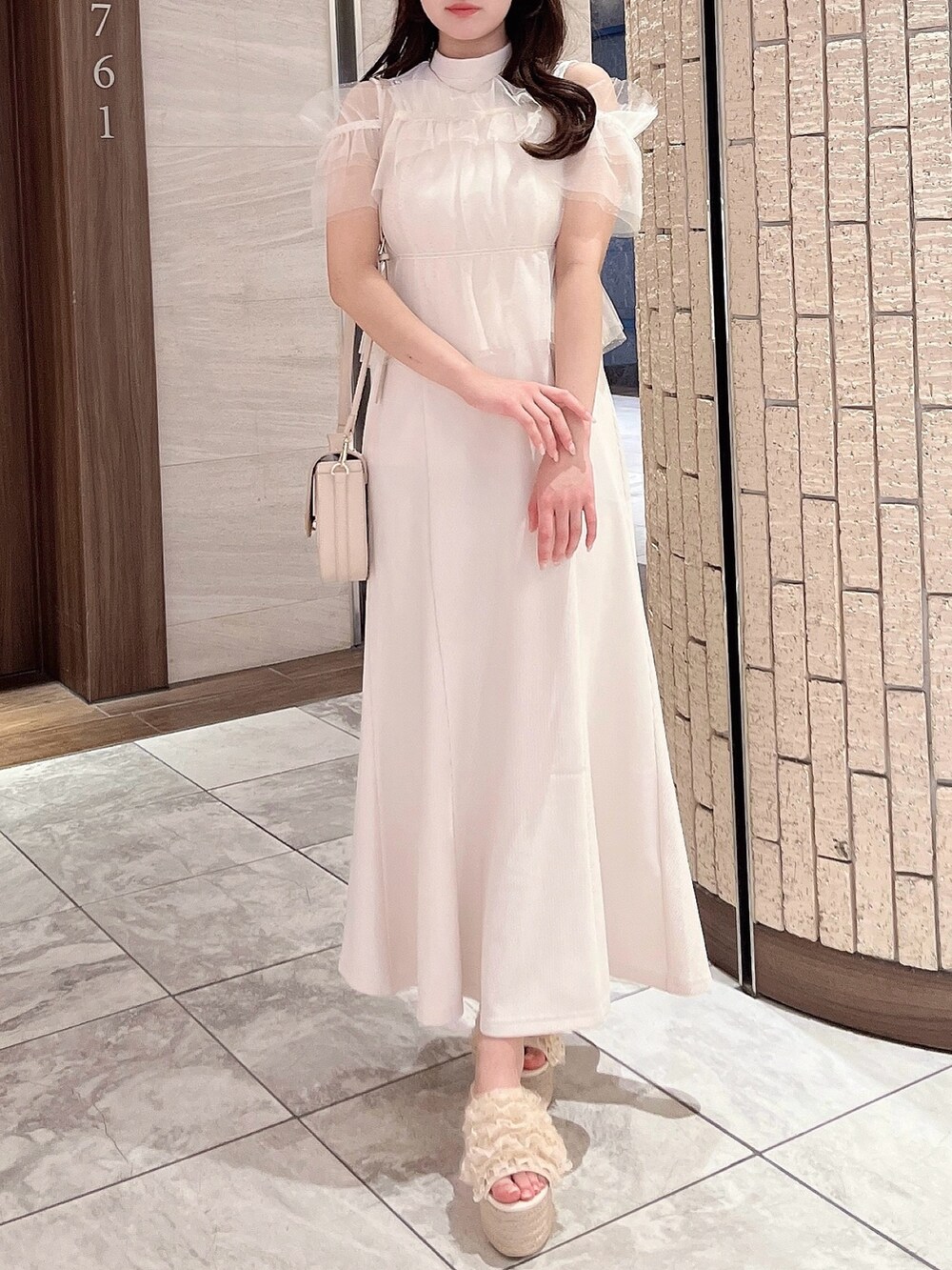 ホワイト系のワンピース、ホワイト系のハンドバッグ、オレンジ系のサンダルを着用したレディースの夏コーディネートの2枚目の写真