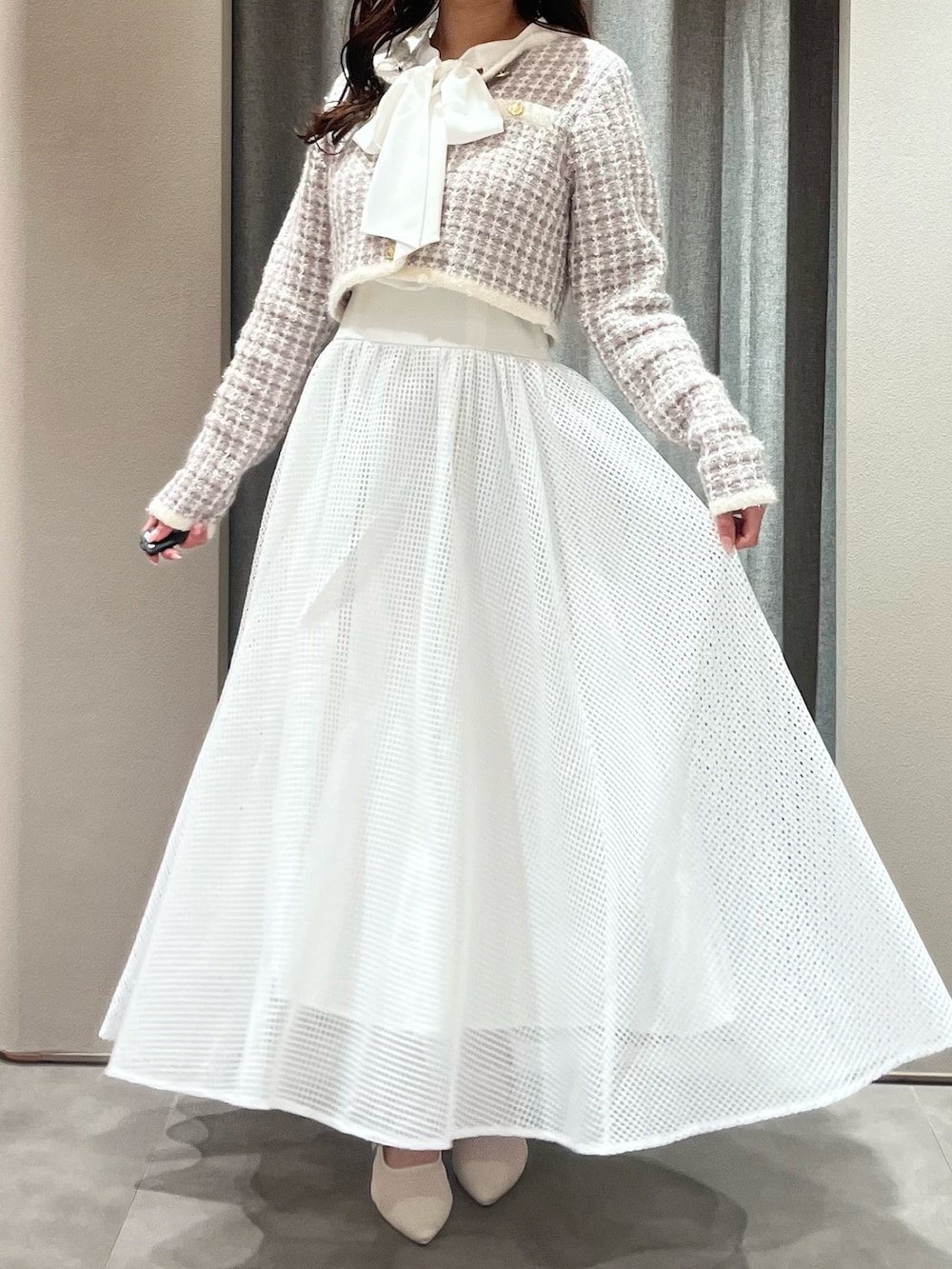 パープル系のノーカラージャケット、ホワイト系のワンピース、ホワイト系のパンプスを着用したレディースの春コーディネートの2枚目の写真