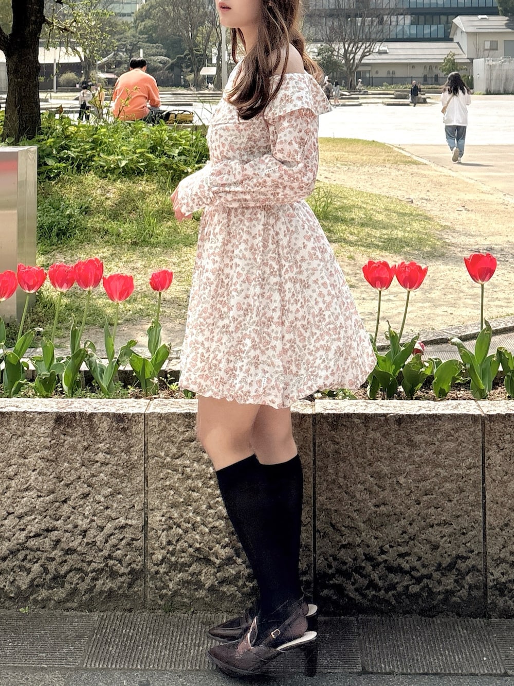 オレンジ系のワンピース、ブラウン系のローファーを着用したレディースの春コーディネートの7枚目の写真