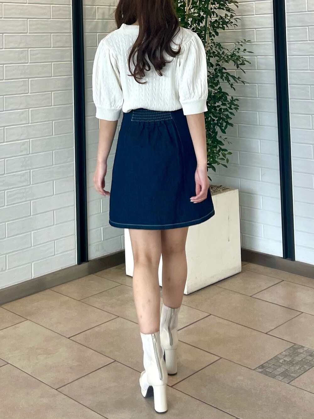ホワイト系のニット/セーター、ブルー系のデニムスカート、ホワイト系のブーツを着用したレディースの春コーディネートの6枚目の写真