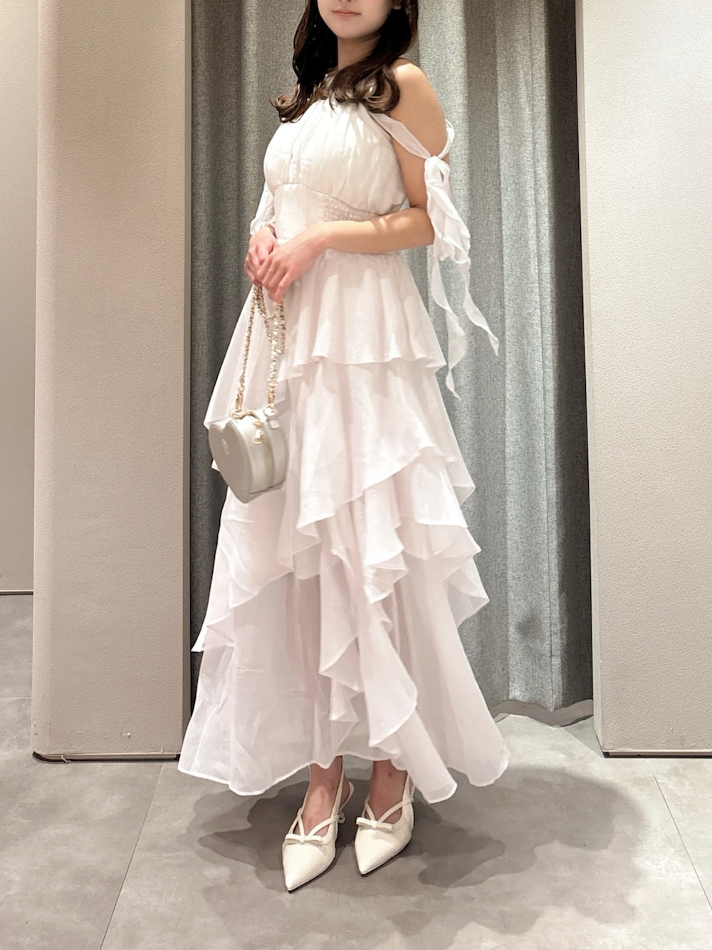 ピンク系のワンピース、シルバー系のショルダーバッグ、ホワイト系のパンプスを着用したレディースの夏コーディネートの6枚目の写真