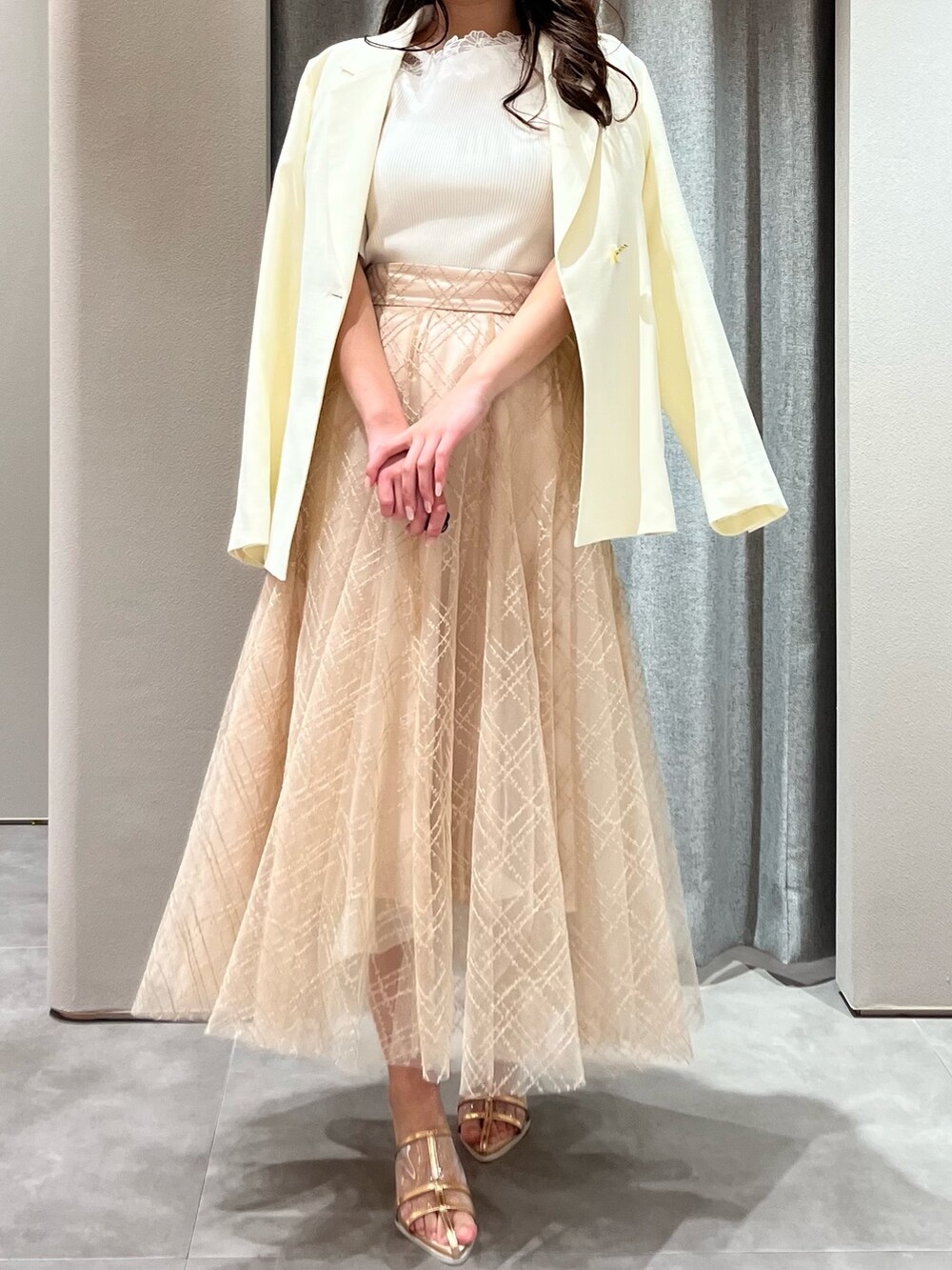 ホワイト系のニット/セーター、ホワイト系のテーラードジャケット、ベージュ系のスカートを着用したレディースの春コーディネートの2枚目の写真