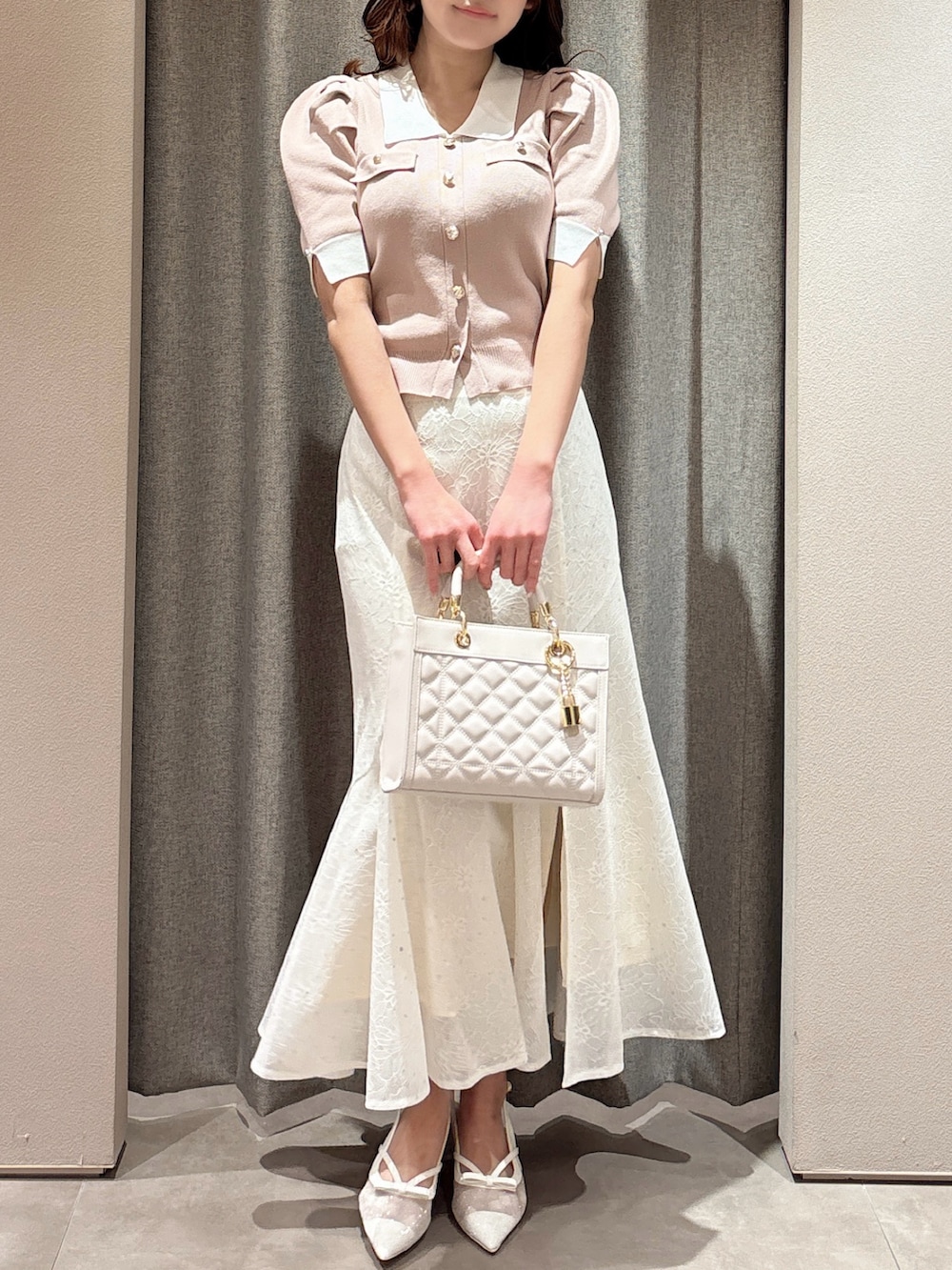 ピンク系のニット/セーター、ピンク系のハンドバッグ、ホワイト系のスカートを着用したレディースの春コーディネートの3枚目の写真