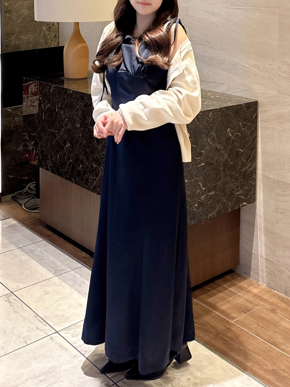 ブルー系のワンピース、ホワイト系のカーディガン/ボレロ、ブラック系のパンプスを着用したレディースの秋コーディネートの5枚目の写真